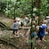 A group of hikers stops in front of a giant tree with roots that rope along the ground